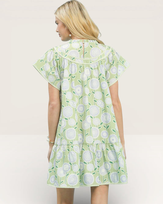 Woman wearing a green floral dress against a plain background