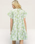Woman wearing a green floral dress against a plain background
