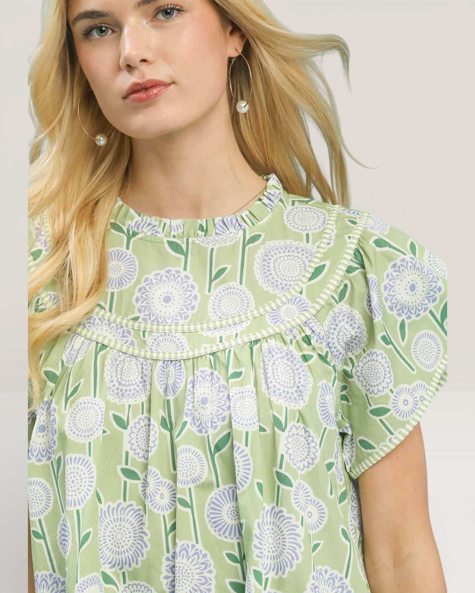 Woman wearing a green floral blouse against a plain background