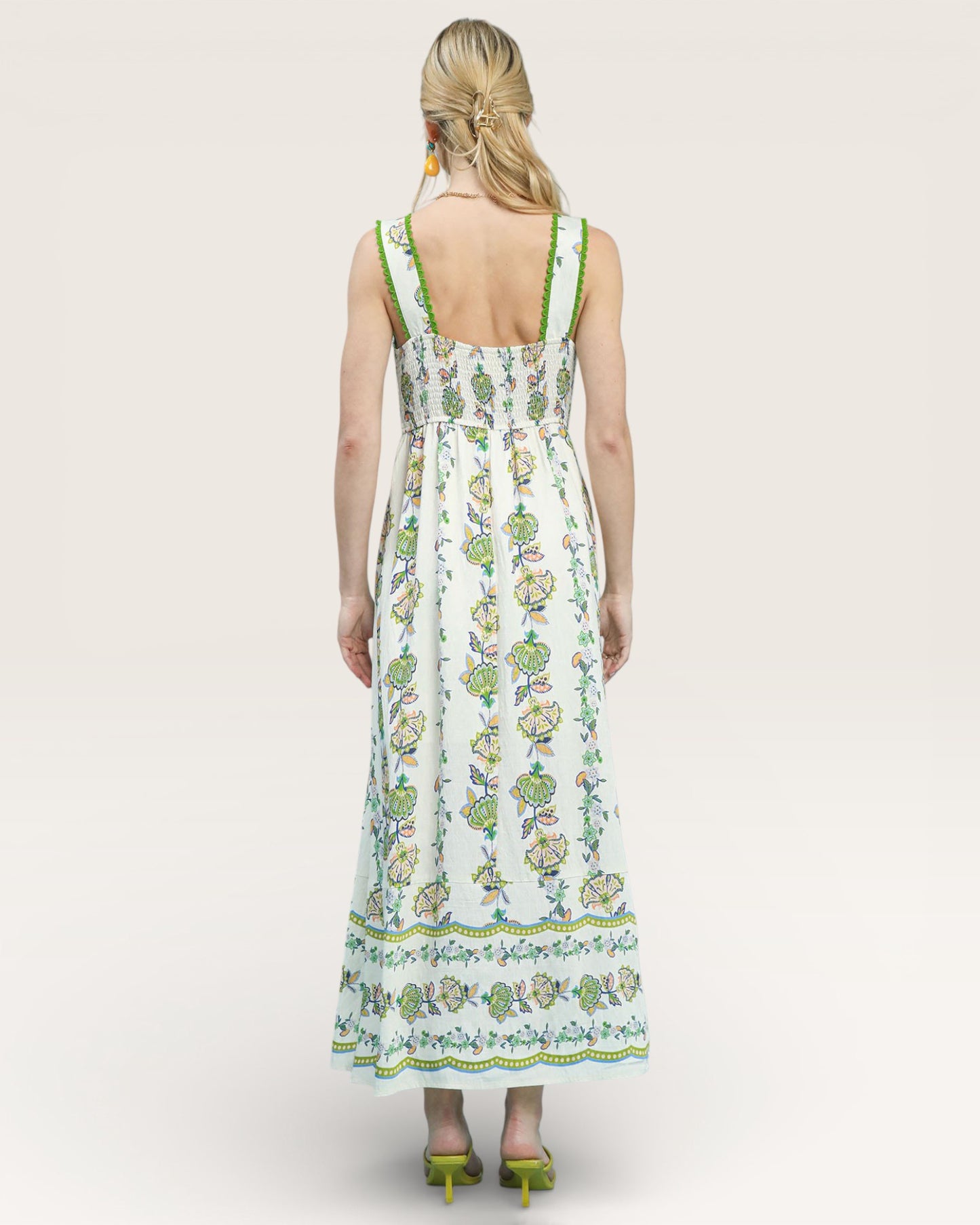 Woman wearing a floral dress with green accents on a white background