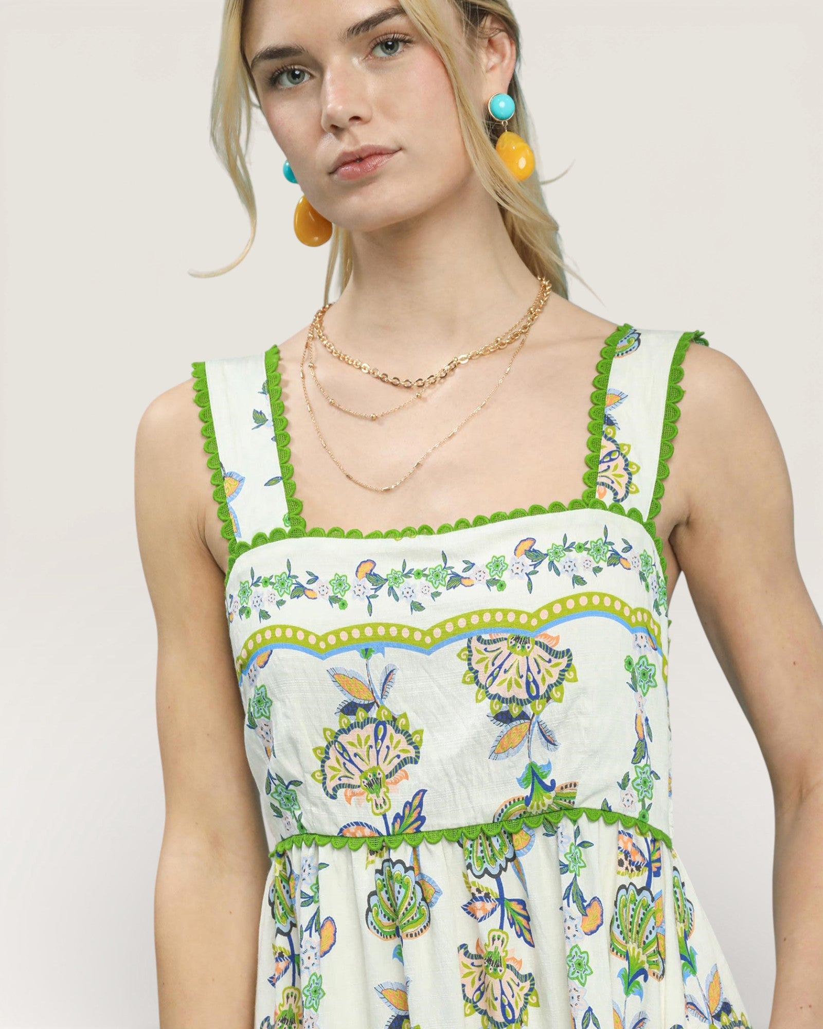 Woman wearing a floral dress with green trim on a plain background