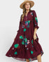 Woman wearing a burgundy dress with floral patterns on a white background