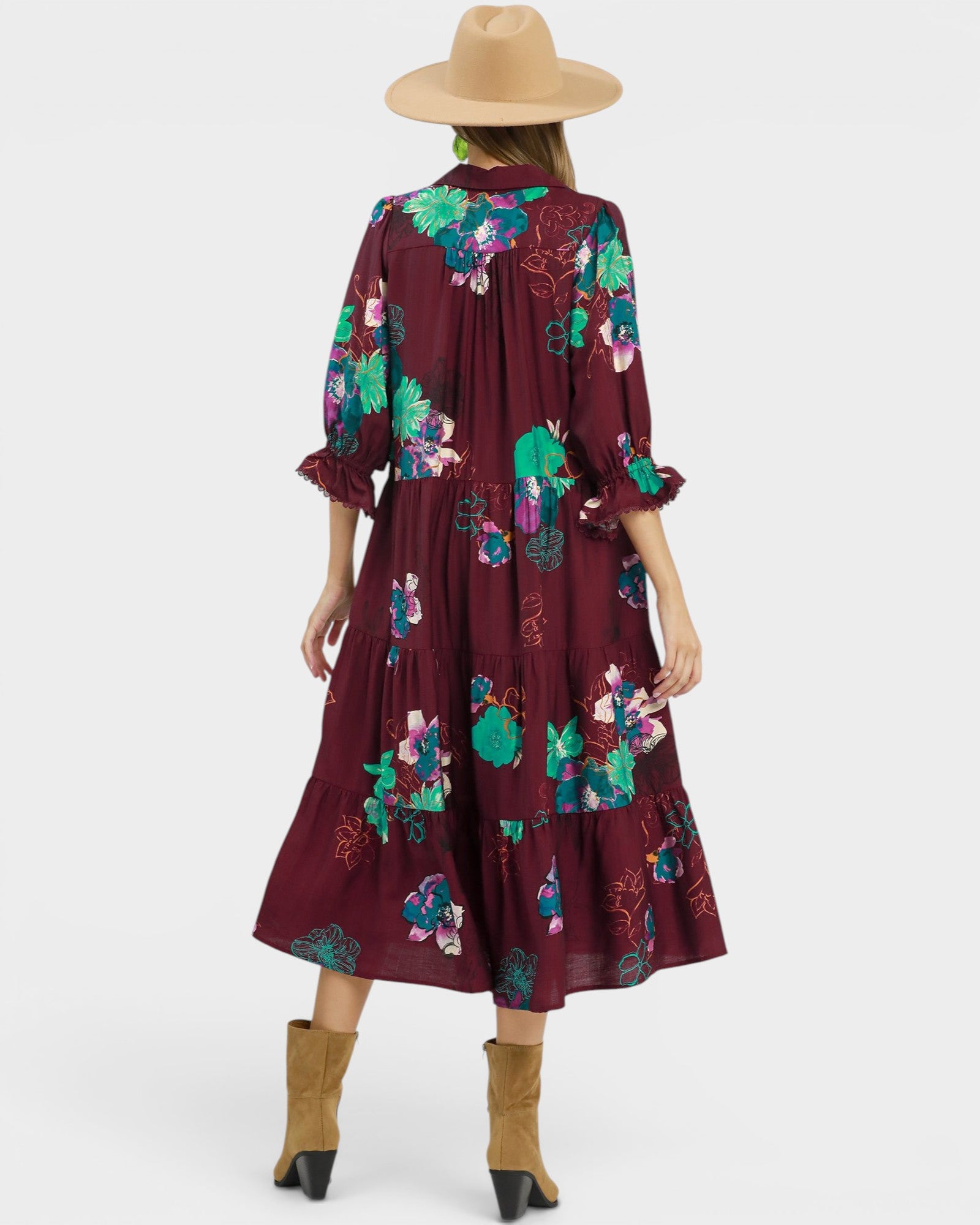 Woman wearing a burgundy floral dress with a beige hat on a white background