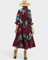 Woman wearing a burgundy floral dress with a beige hat on a white background