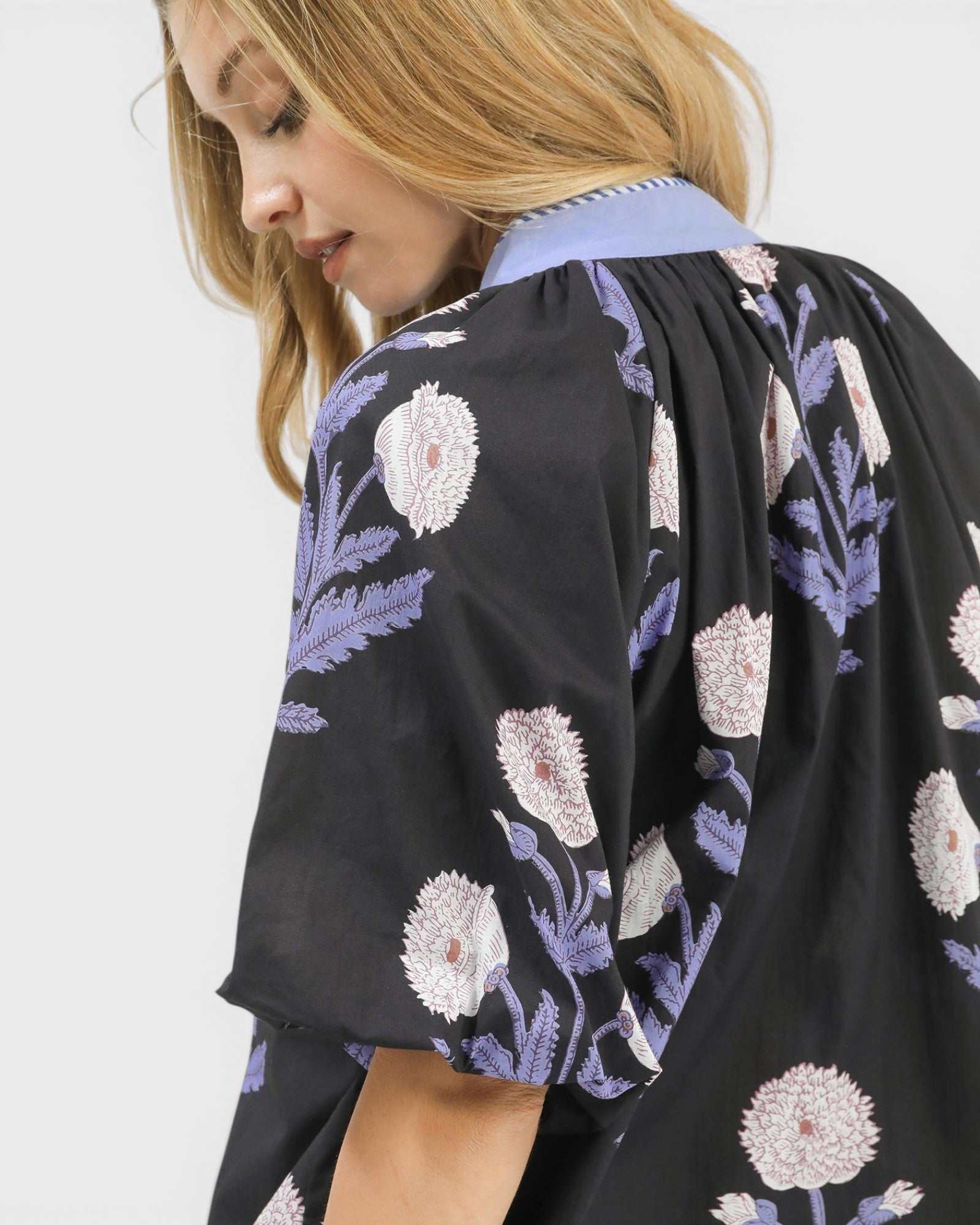 Woman wearing a black floral kimono-style garment on a white background