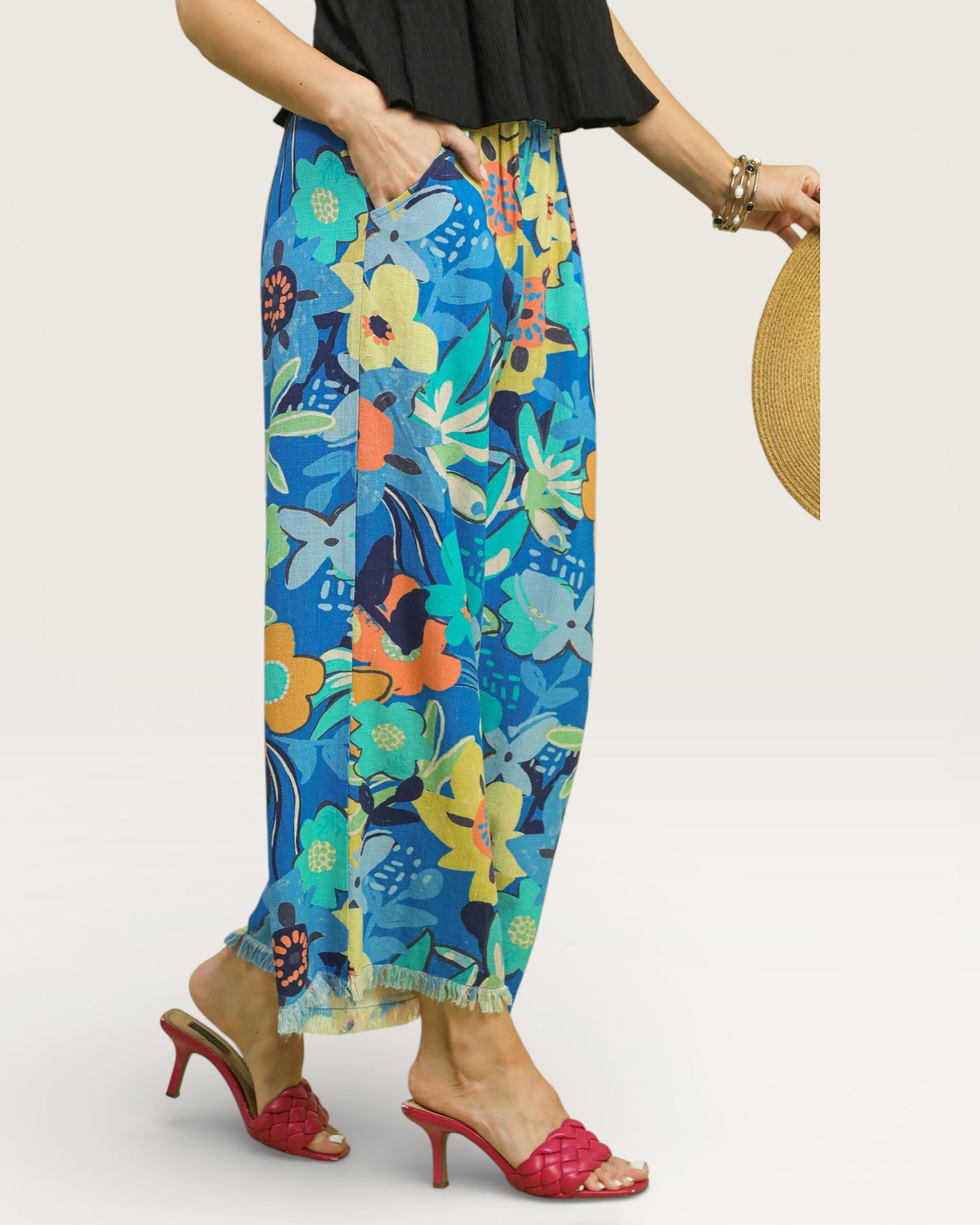Woman wearing colorful floral pants with a plain background