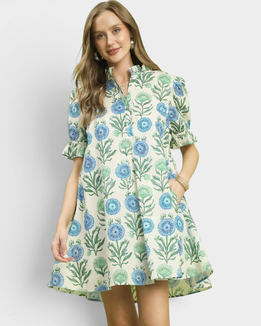 Woman wearing a floral dress with blue and green flowers on a plain background