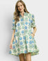 Woman wearing a floral dress with blue and green flowers on a plain background