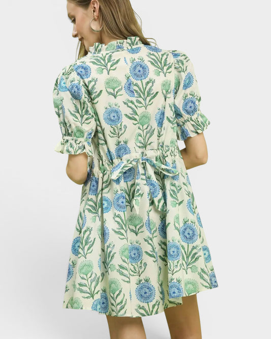 Woman wearing a floral dress with blue and green flowers on a white background