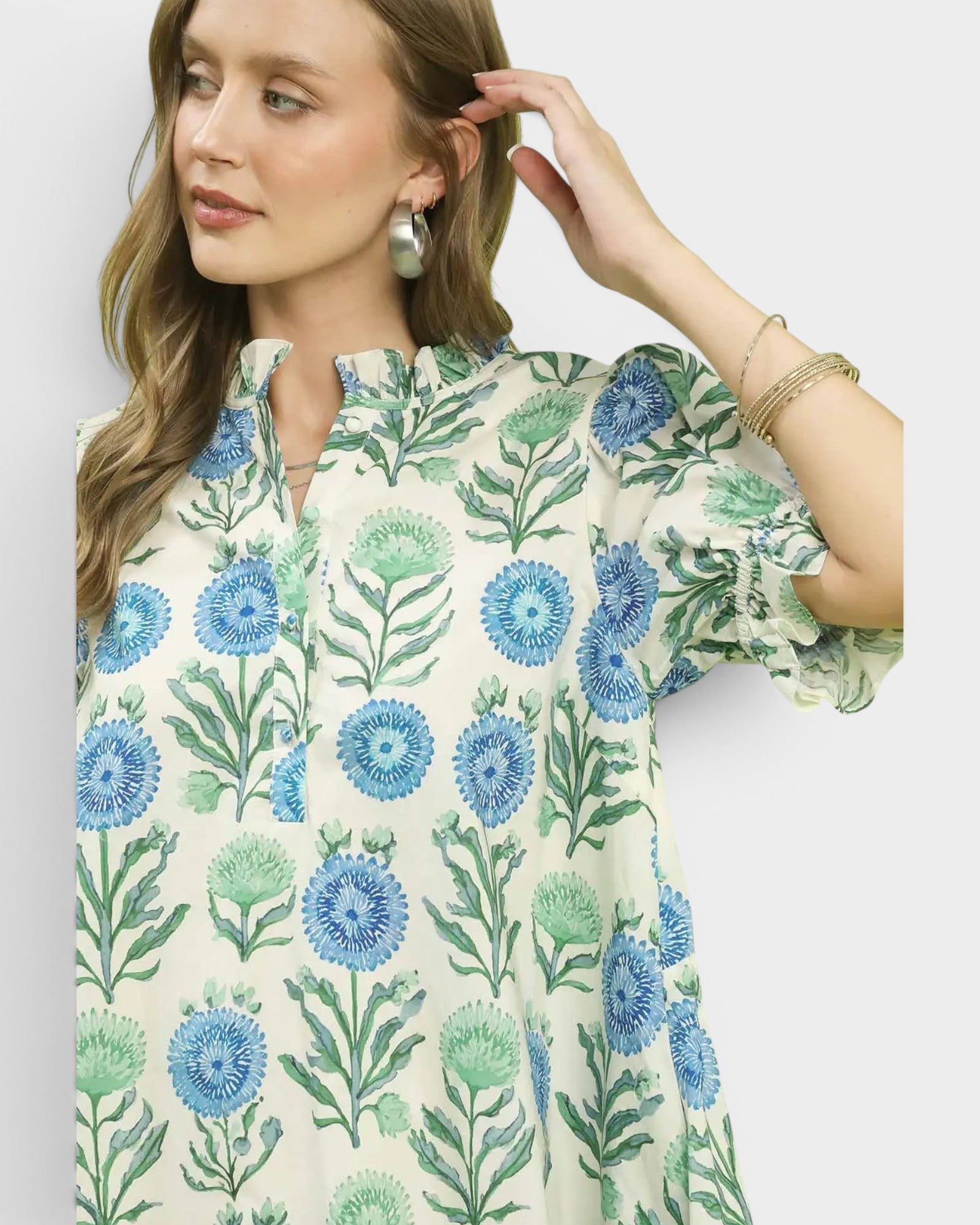 Woman wearing a floral patterned shirt with blue and green flowers on a white background