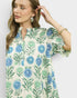 Woman wearing a floral patterned shirt with blue and green flowers on a white background