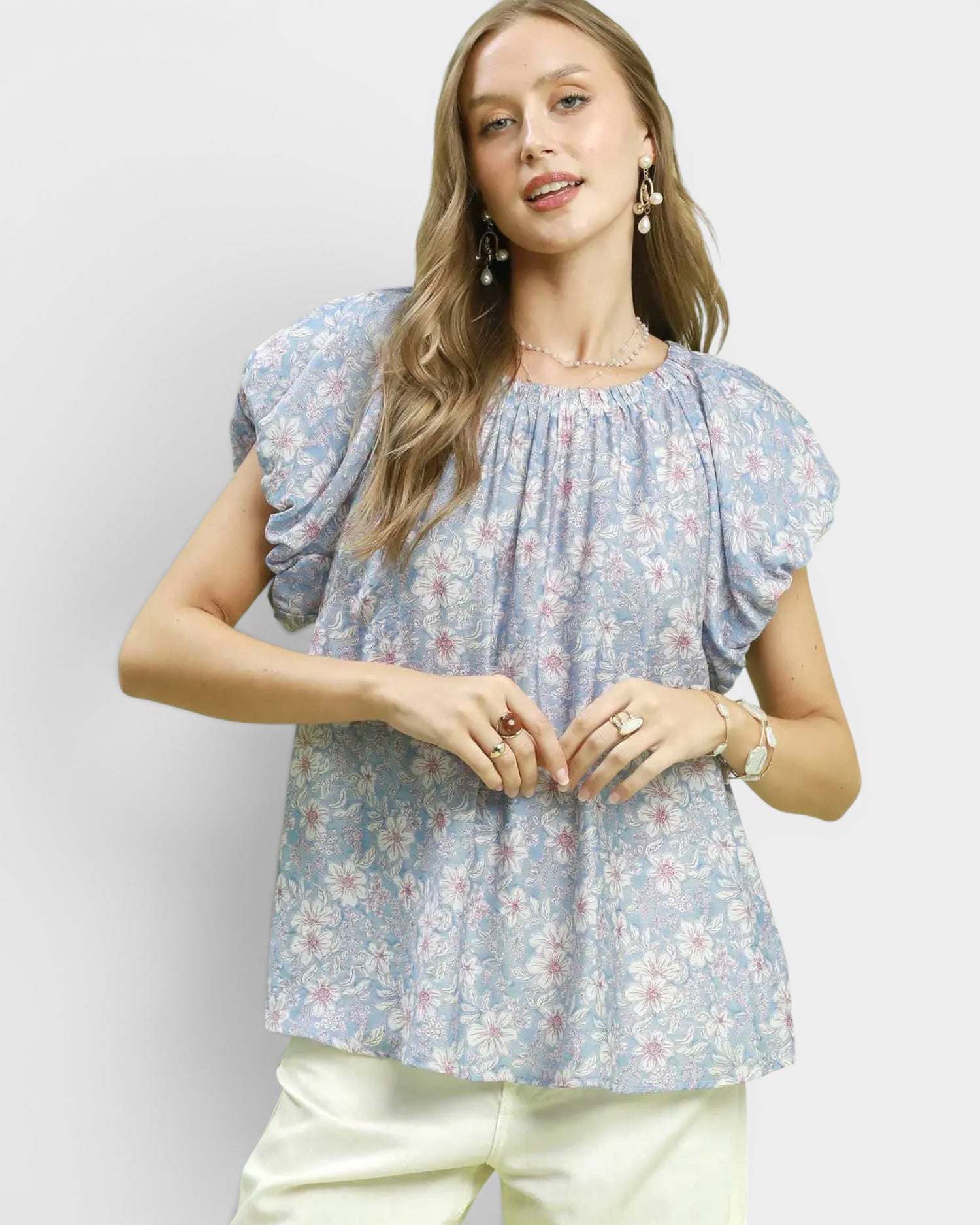 Woman wearing a floral blouse with puff sleeves against a plain background