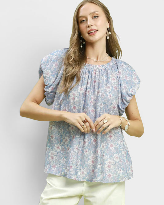 Woman wearing a floral blouse with puff sleeves against a plain background