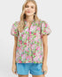 Woman wearing a colorful floral blouse and blue shorts on a white background