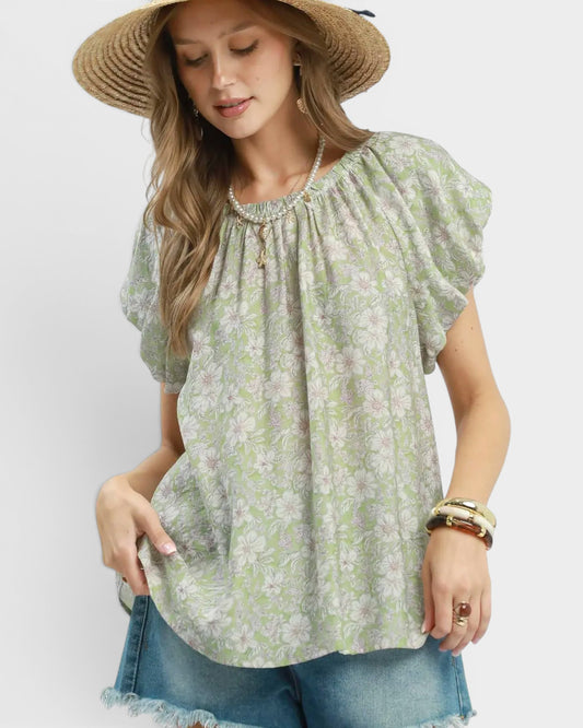 Woman wearing a green floral blouse and straw hat on a white background
