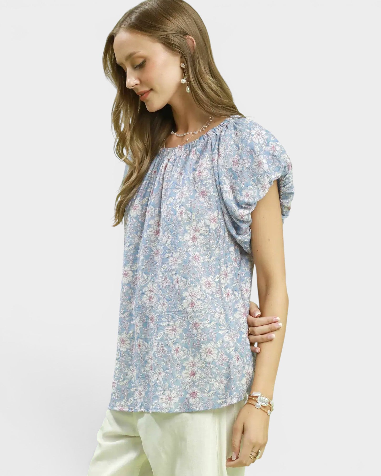 Woman wearing a light blue floral blouse against a white background
