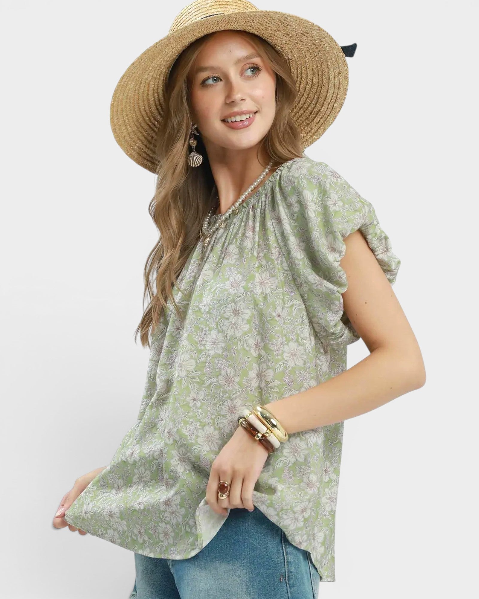 Woman wearing a green floral blouse and straw hat on a white background