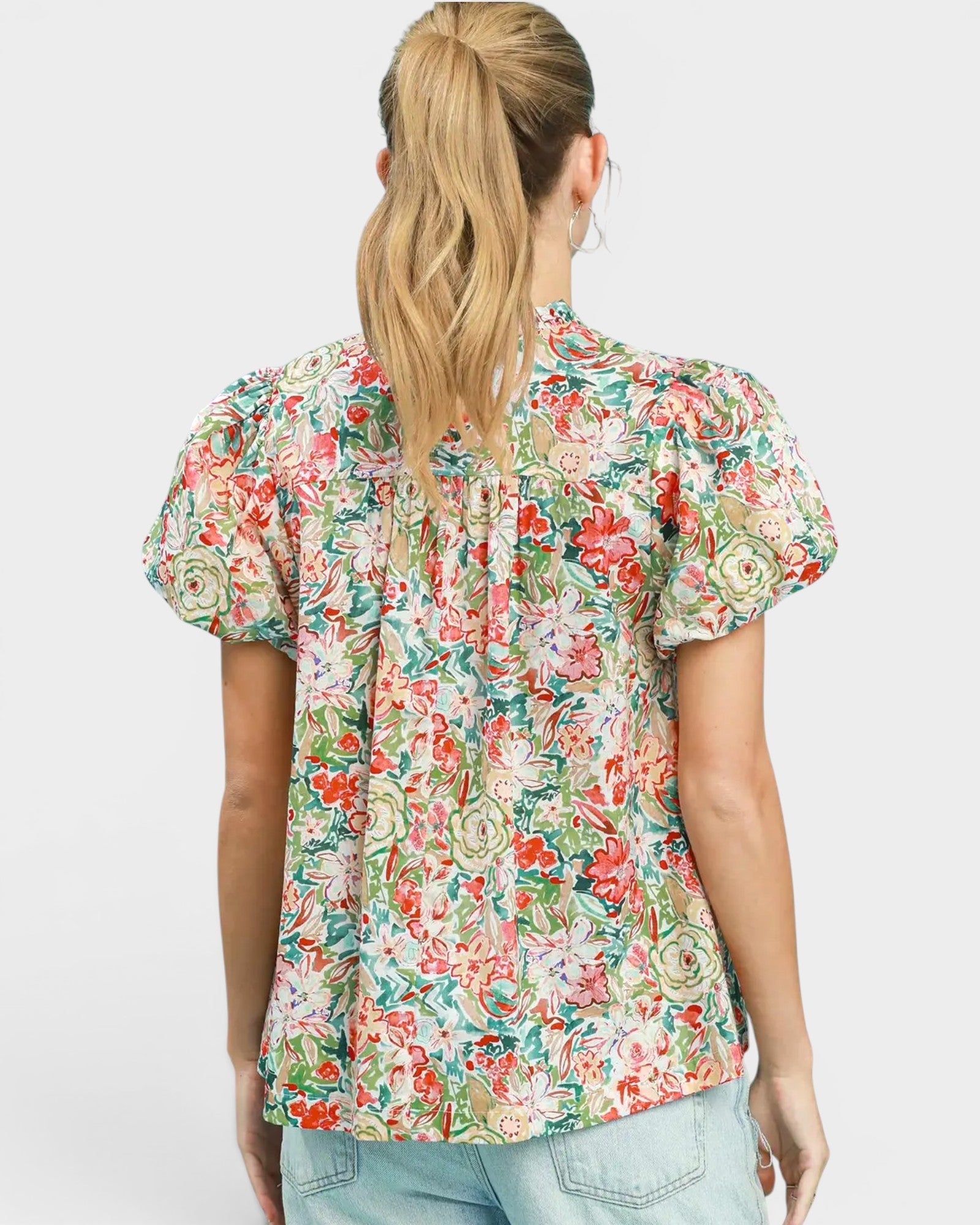 Woman wearing a floral blouse with puff sleeves on a plain background