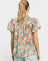 Woman wearing a floral blouse with puff sleeves on a plain background