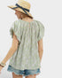 Woman wearing a floral blouse and straw hat with a blue ribbon on a white background