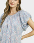 Woman wearing a light blue floral blouse against a white background