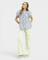 Woman wearing a floral blouse and light-colored pants on a white background