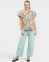 Woman wearing a floral blouse and light blue jeans on a white background