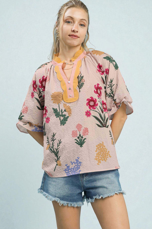 Woman wearing a floral blouse and denim shorts against a light blue background