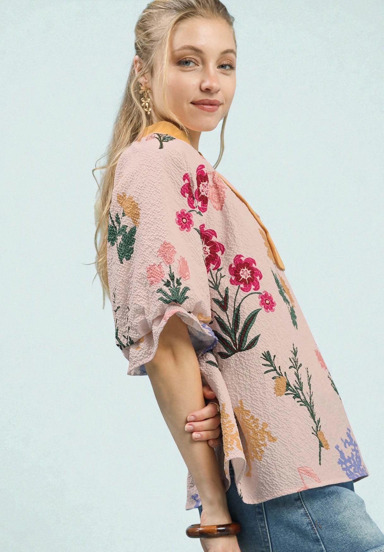 Woman wearing a floral kimono-style top against a light blue background