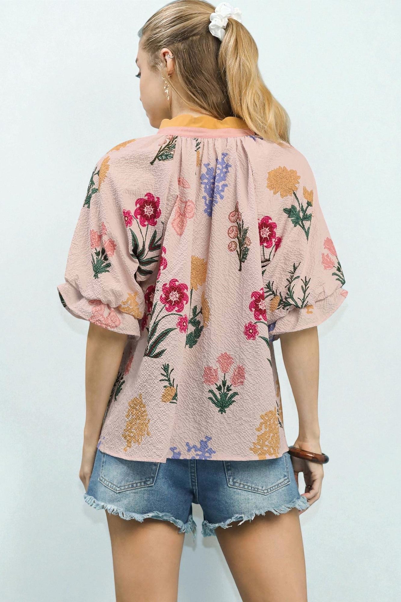 Woman wearing a floral kimono-style top and denim shorts against a light background