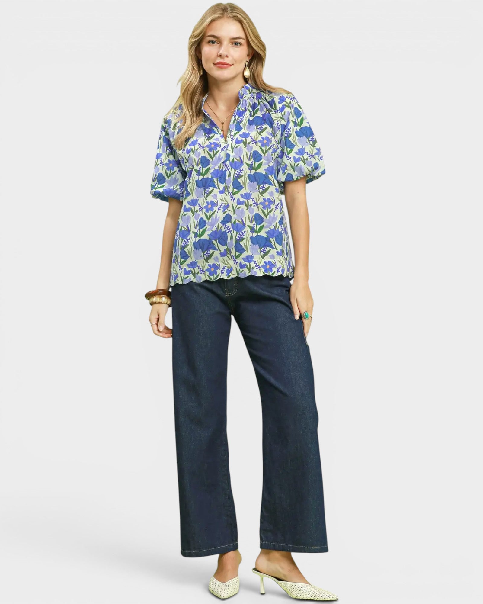 Woman wearing a floral blouse and dark jeans on a white background