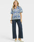 Woman wearing a floral blouse and dark jeans on a white background