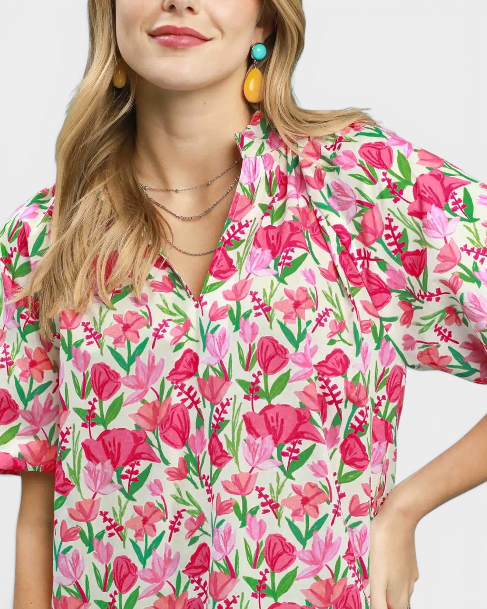 Woman wearing a floral blouse with pink and green flowers on a white background