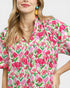 Woman wearing a floral blouse with pink and green flowers on a white background