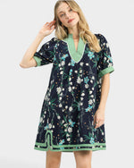 Woman wearing a navy floral dress with green trim on a white background