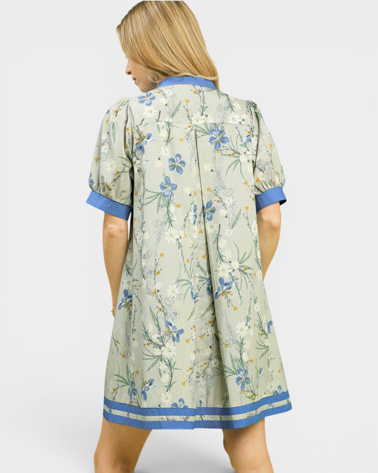 Woman wearing a floral dress with blue accents on a white background