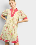 Woman wearing a floral dress with pink accents on a plain background