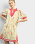 Woman wearing a floral dress with pink accents on a plain background