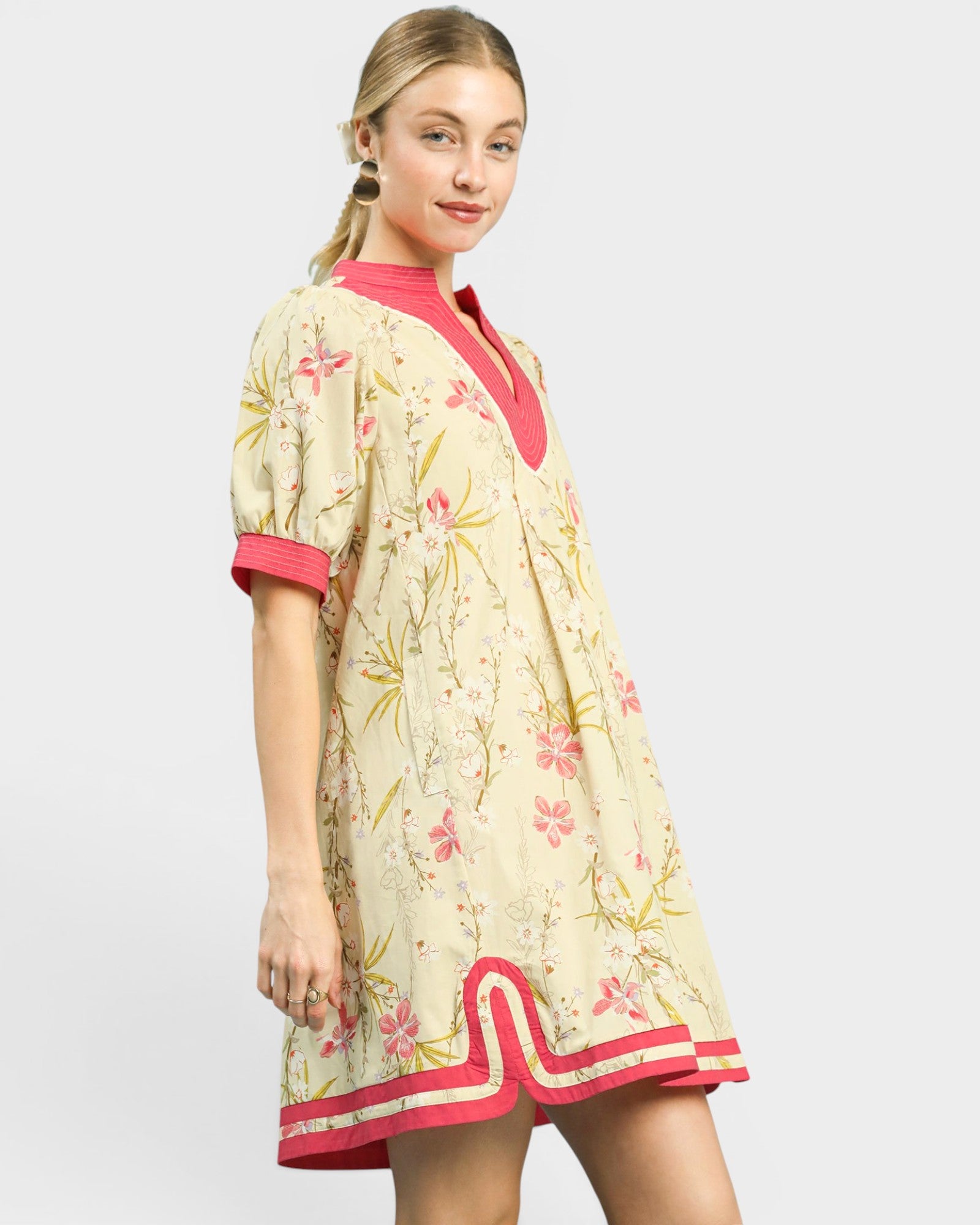 Woman wearing a floral dress with pink accents on a white background