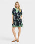 Woman wearing a floral dress with green accents on a white background