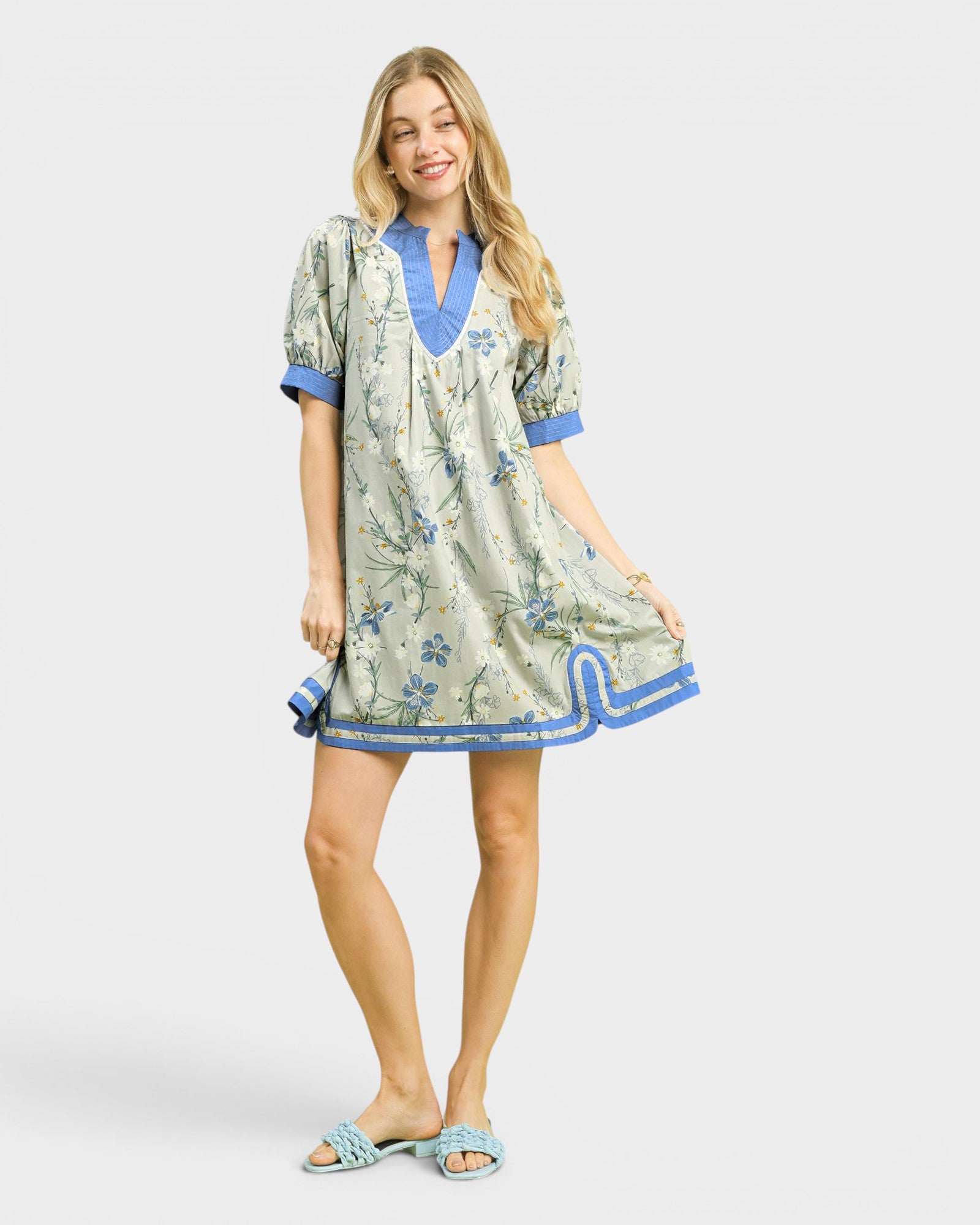 Woman wearing a floral dress with blue accents on a white background
