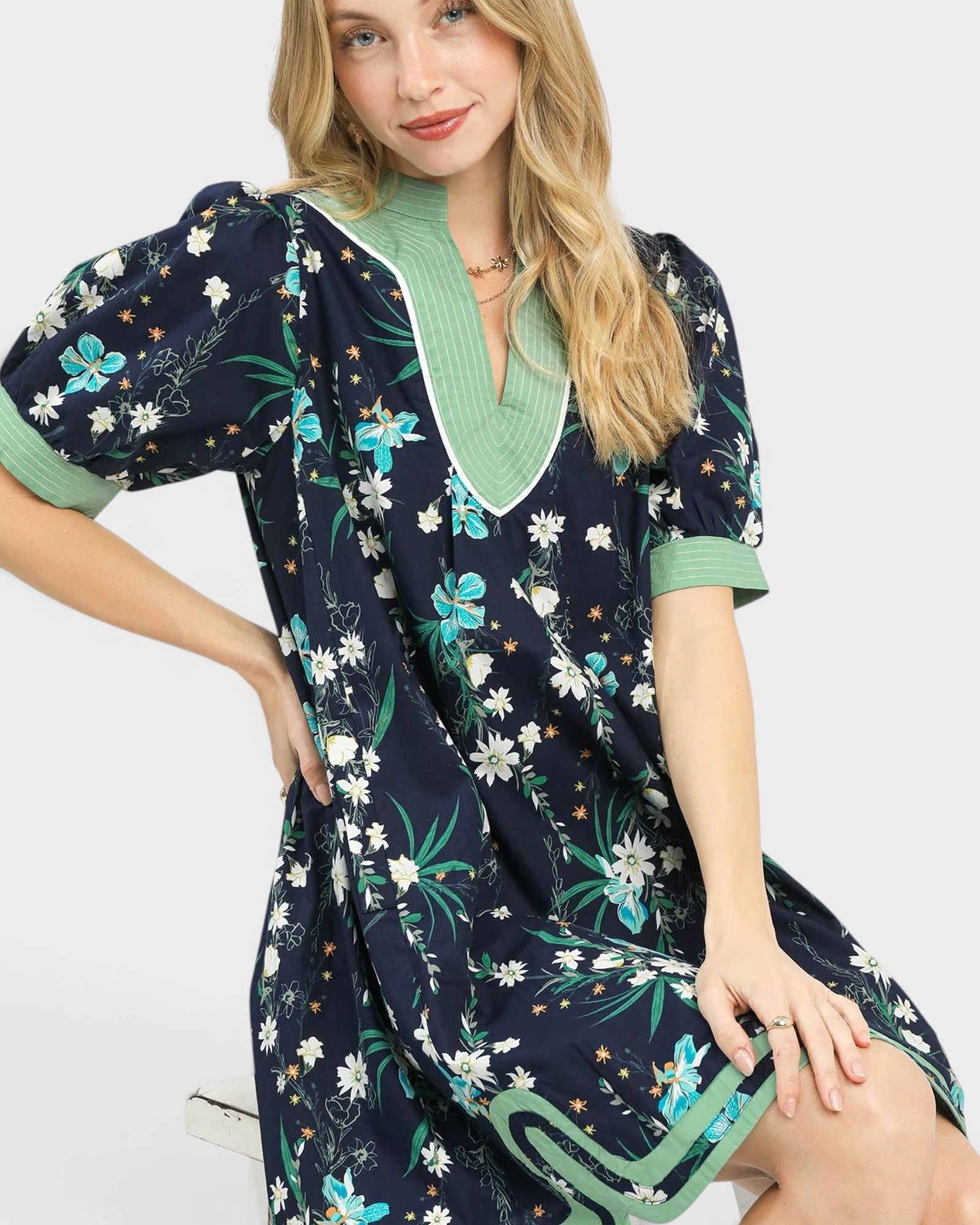 Woman wearing a navy floral dress with green accents on a white background