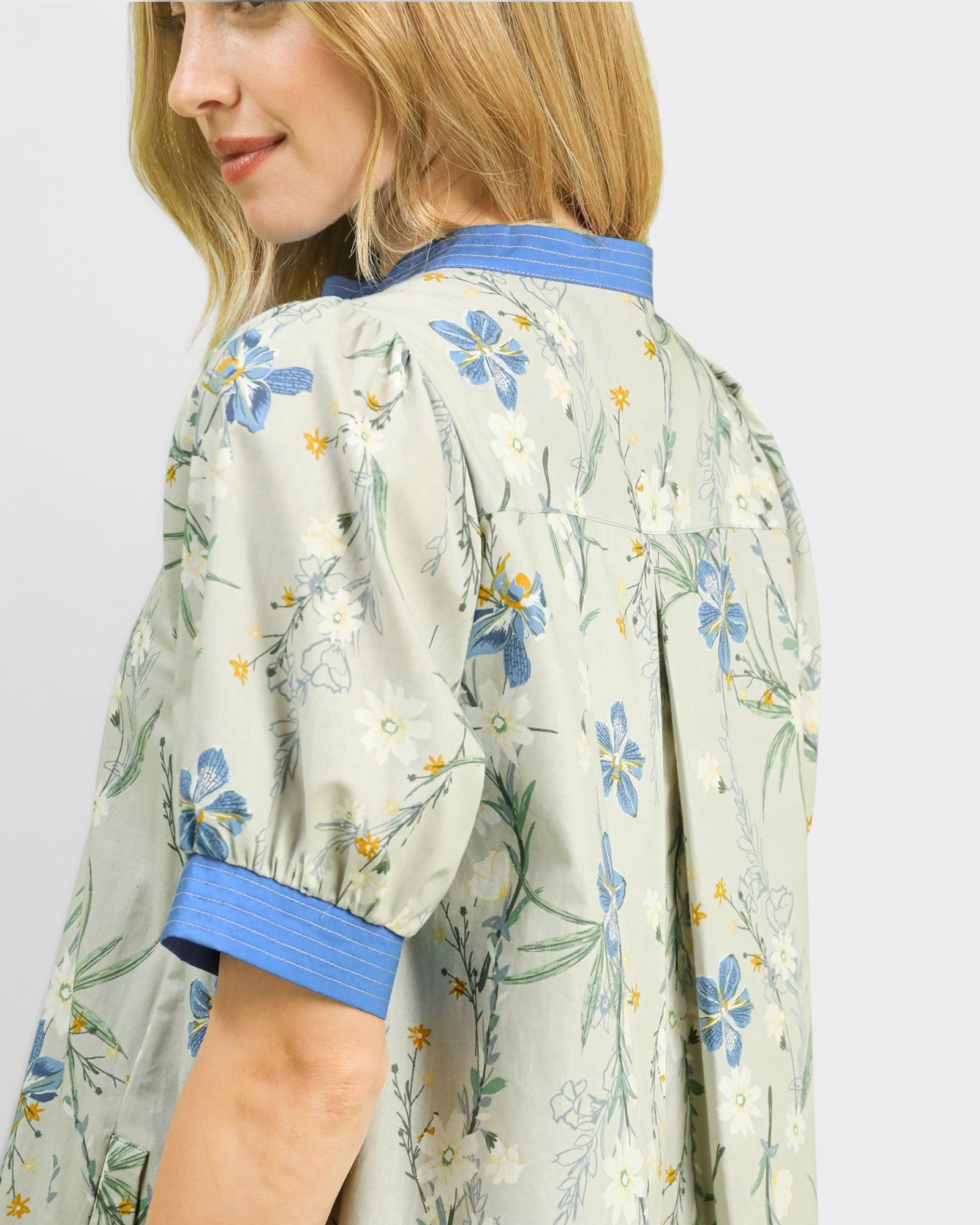 Woman wearing a floral kimono-style dress with blue accents on a plain background