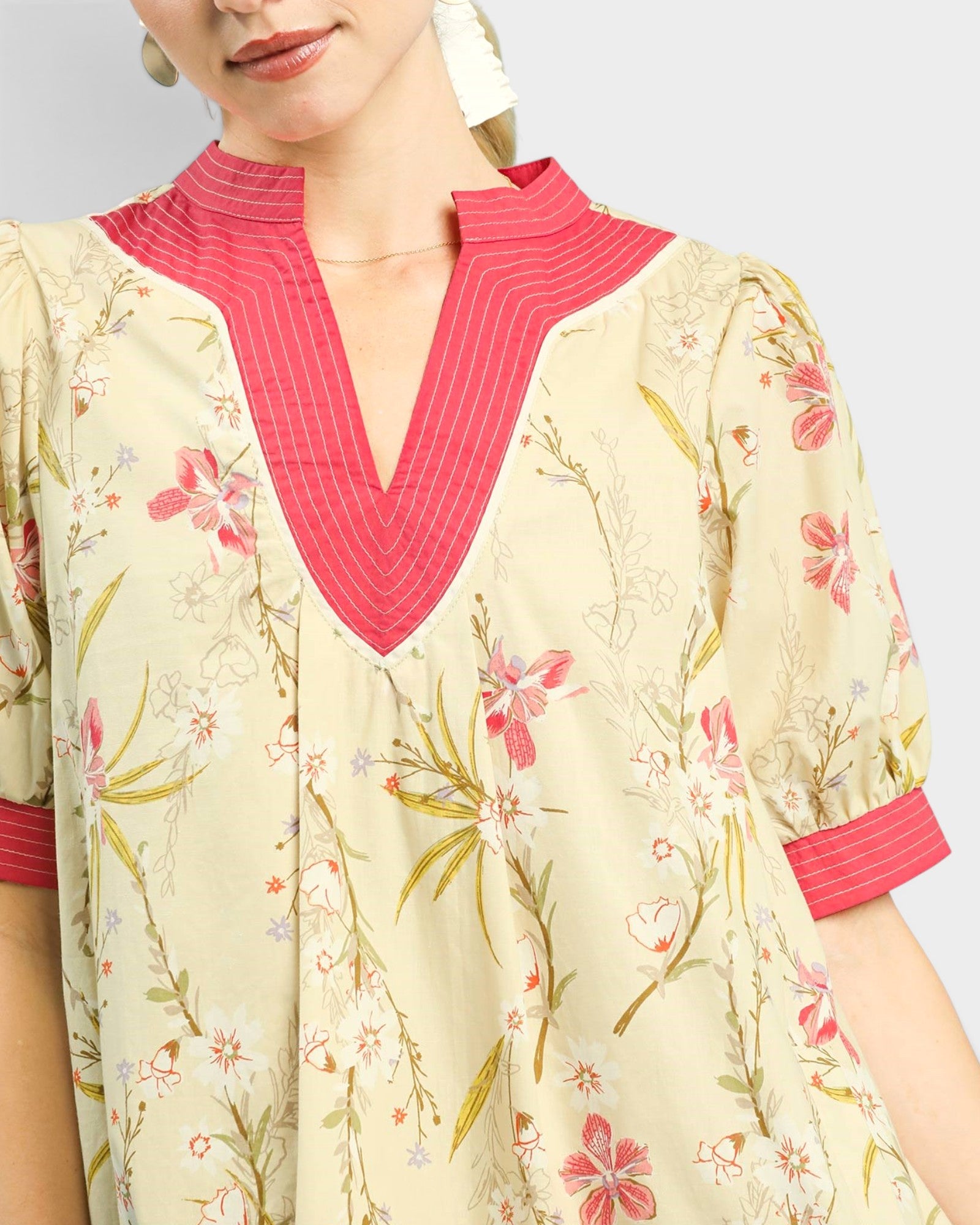 Woman wearing a floral dress with pink accents on a plain background
