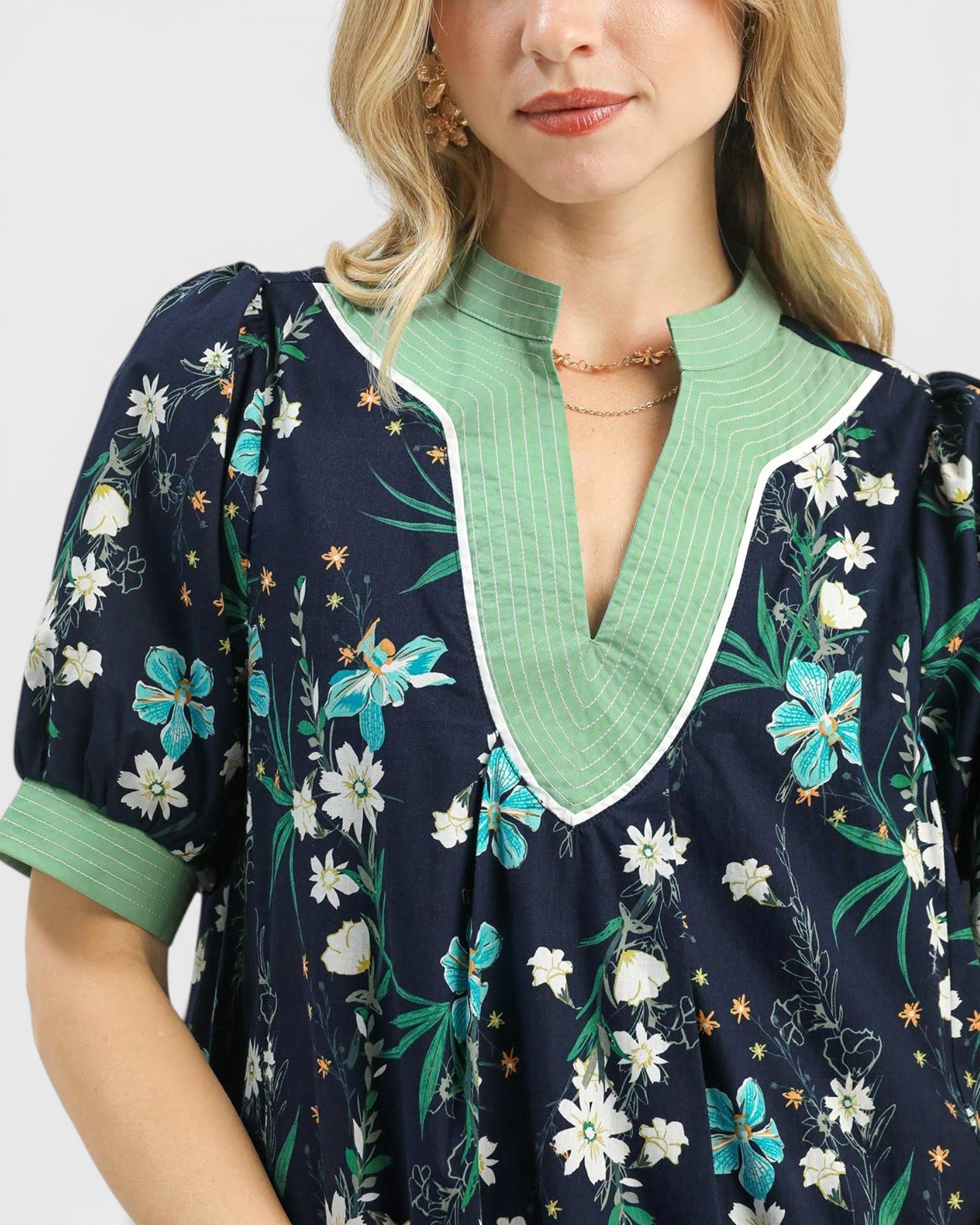 Woman wearing a navy floral dress with green trim on a white background