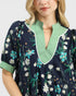 Woman wearing a navy floral dress with green trim on a white background