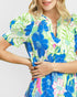 Woman wearing a colorful floral dress on a plain background