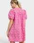 Woman wearing a pink dress with white floral pattern on a white background