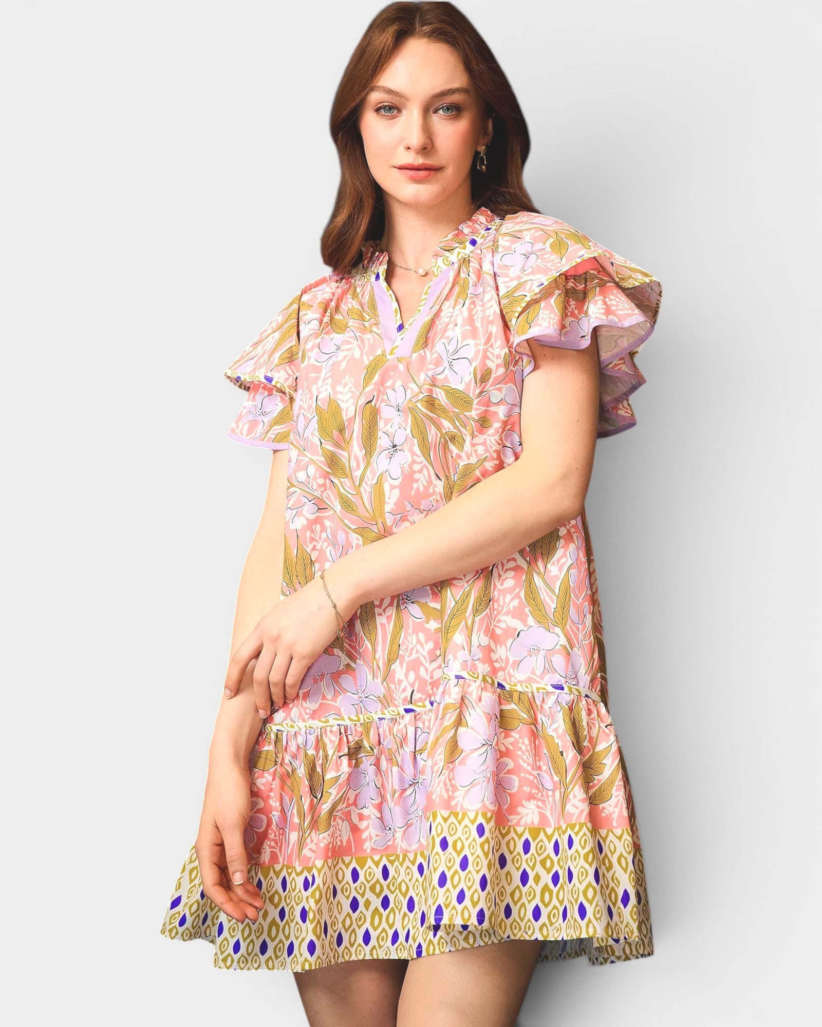 Woman wearing a floral dress with ruffled sleeves on a plain background