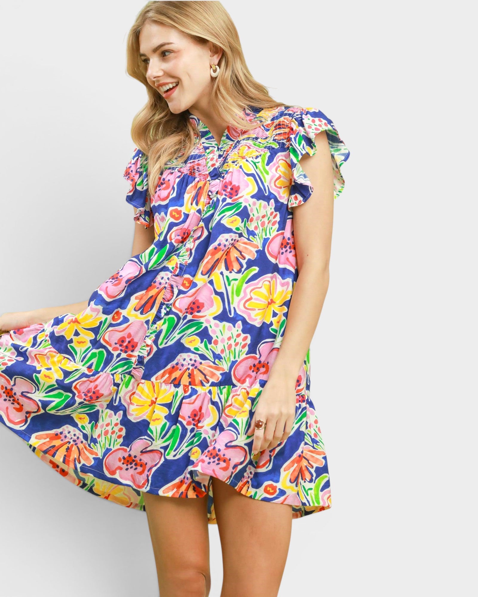 Woman wearing a colorful floral dress against a plain background